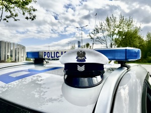Zdjęcie przedstawia czapkę policyjną na oznakowanym radiowozie.